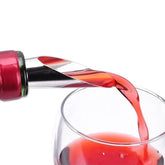 Gros plan sur le bec verseur anti-goutte fixé sur une bouteille de vin rouge, en train de verser dans un verre.