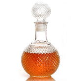 Carafe à whisky ancienne en verre taillé motif diamant, remplie de whisky ambré, sur fond blanc.