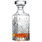Carafe à whisky en cristal taillé avec bouchon, remplie de whisky ambré, présentée sur fond blanc