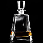 Carafe à whisky en cristal transparent avec bouchon facetté, remplie de whisky ambré, photographiée sur fond noir.
