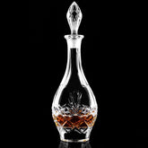 Packshot de la carafe à whisky en cristal taillé, remplie d'ambre, sur fond noir studio.