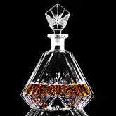 Carafe à whisky en cristal taillé remplie d'alcool ambré, photographiée en gros plan sur fond noir.