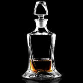 Carafe à whisky design en cristal transparent remplie d'alcool ambré, photographiée en packshot sur fond noir avec reflet.