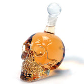 Carafe à whisky en forme de tête de mort remplie de liquide ambré, photographiée de profil sur fond blanc avec son bouchon en cristal taillé