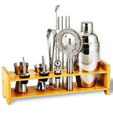 Kit à cocktail complet avec tous ses accessoires en inox présenté sur son support en bambou, fond blanc