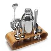 Autre angle du même kit cocktail sur son socle en bambou, mettant en valeur la cuillère à mélange, la passoire, le pilon, le shaker et le tire-bouchon.