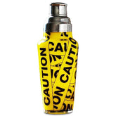 Shaker à cocktail avec motif ruban de signalisation jaune et noir façon bande de chantier, photographié sur fond blanc.