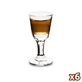 Verre à shot à pied pour rhum rempli d'une dose ambrée, photographié seul sur fond blanc.