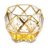 Verre à whisky de luxe au design géométrique doré, photographié sur fond blanc