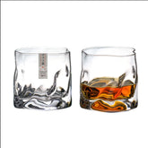 Duo de verres à whisky japonais côte à côte, l'un vide avec son étiquette d'origine, l'autre rempli de whisky ambré, sur fond blanc.
