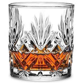 Verre à whisky vintage en cristal taillé rempli de whisky ambré, photographié sur fond blanc.