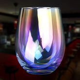 Verre à cocktail Arc En Ciel en cristal, vide, aux reflets irisés multicolores, photographié dans un bar à l'ambiance tamisée