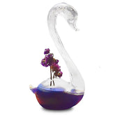 Verre à cocktail cygne au col transparent et à la base en verre irisé bleu-violet, décoré de fleurs séchées violettes, sur fond blanc