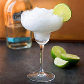 Verre à margarita glacée au citron vert avec une bouteille de tequila en arrière-plan