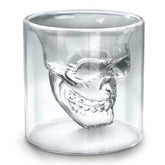 Verre à cocktail tête de mort vide, vu de profil sur fond blanc, laissant apparaître le crâne sculpté en relief.