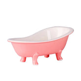 Verre en forme de baignoire rose posé sur fond blanc, vue de profil sur ses pieds ornementés
