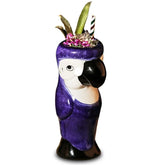 Verre à cocktail perroquet violet sur fond blanc, vue de face avec garniture ananas et paille rayée.