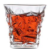 Verre à whisky moderne facetté rempli d'une boisson ambrée, photographié sur fond blanc