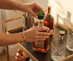 Mains fixant le bec verseur 3 cl sur une bouteille d'amaretto posée sur un chariot à bar