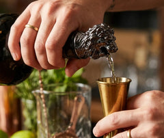 Bec verseur tête de lion utilisé pour verser une liqueur dans un verre doseur en cuivre