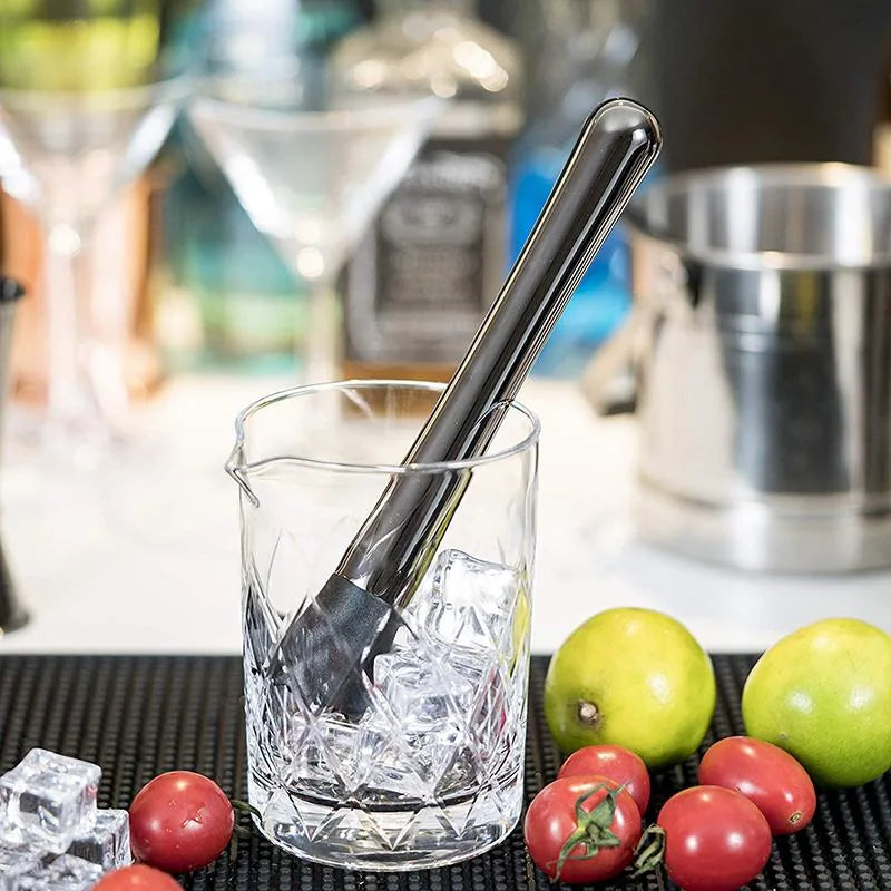 Gros plan sur la cuillère torsadée du kit plongée dans un verre à mélange rempli de glaçons