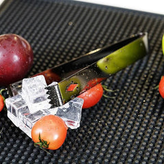 Gros plan sur la pince à glaçons dentelée du kit entourée de tomates cerises et d'un citron vert
