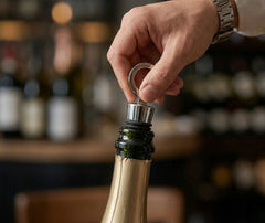Gros plan sur une main tenant l'anneau du bouchon de vin réutilisable pour l'insérer dans une bouteille
