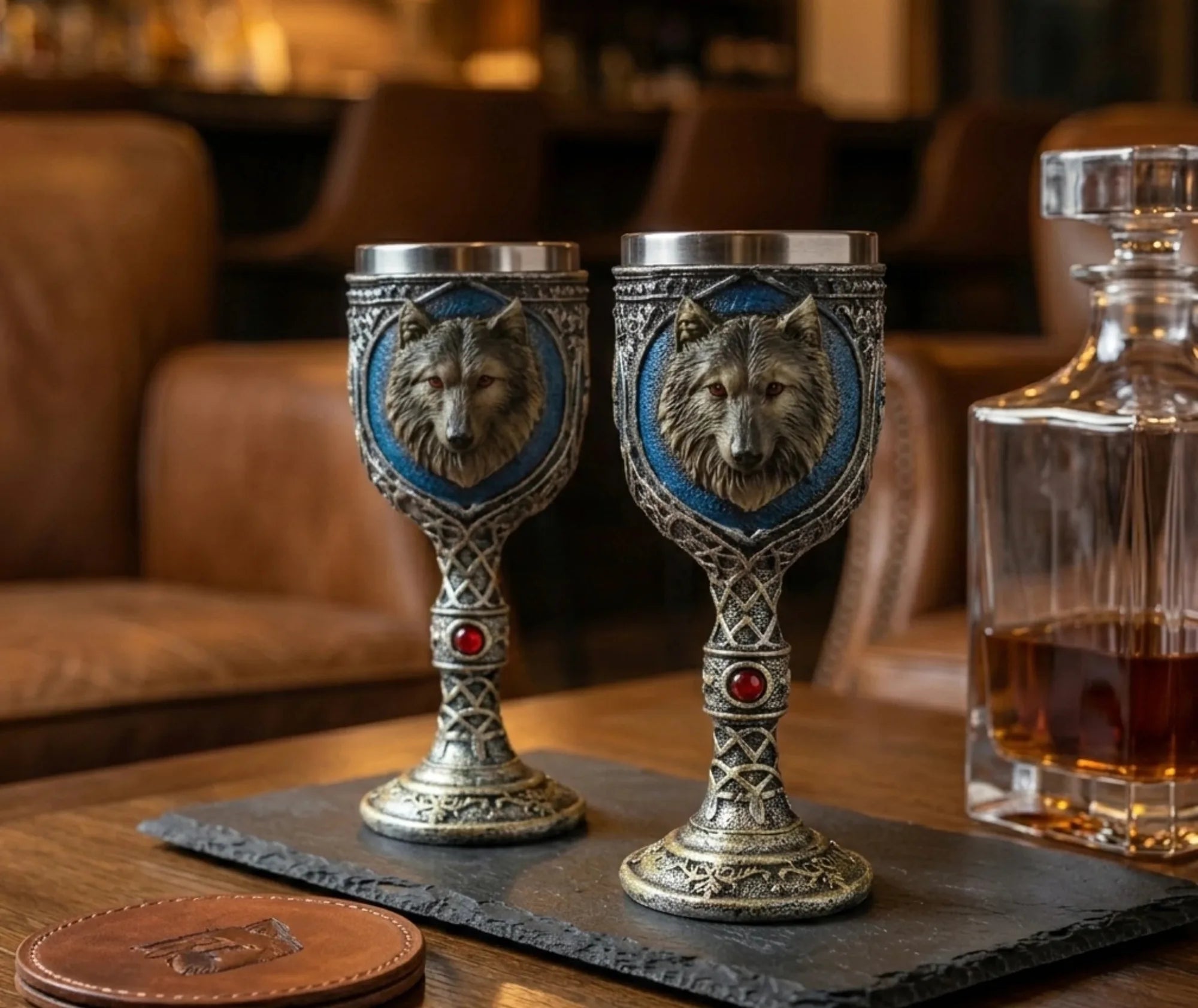 Deux calices Loup posés sur un plateau en ardoise dans un bar en cuir avec une carafe de whisky