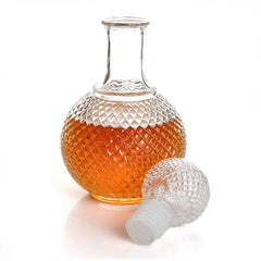 Carafe à whisky ancienne avec son bouchon boule en verre taillé posé à côté, fond blanc.