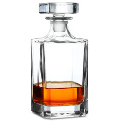Carafe à whisky carrée en cristal remplie d'un tiers de whisky ambré, photographiée sur fond blanc.