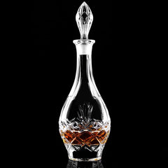 Packshot de la carafe à whisky en cristal taillé, remplie d'ambre, sur fond noir studio.