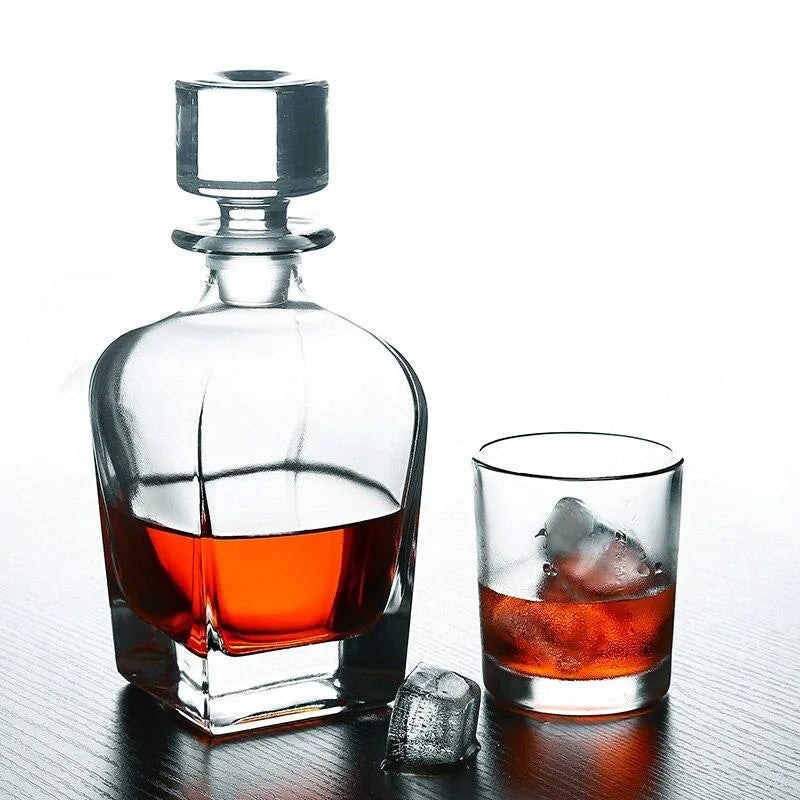 Carafe à whisky remplie posée à côté d'un verre à whisky avec glaçons, sur fond blanc.