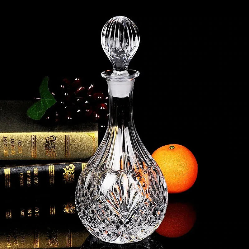 Nature morte de la carafe à whisky en cristal avec des livres reliés, une grappe de raisin et une orange sur fond noir