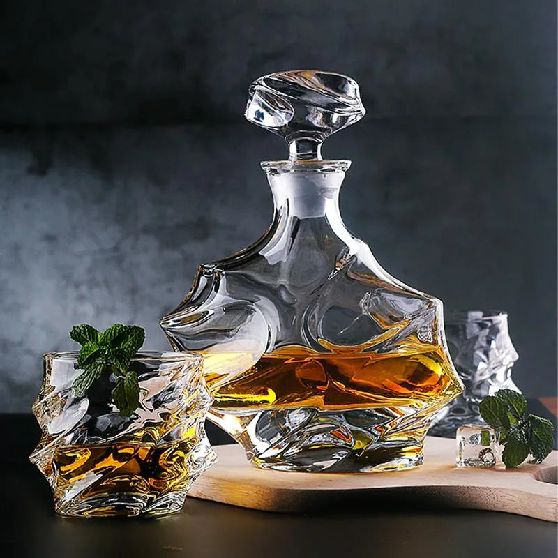 Carafe vague et deux verres assortis garnis de menthe fraîche, disposés sur une planche en bois sur fond gris anthracite.