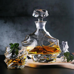 Carafe vague et deux verres assortis garnis de menthe fraîche, disposés sur une planche en bois sur fond gris anthracite.