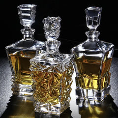 Trois carafes à whisky en cristal aux designs différents, remplies d'alcool ambré, posées sur fond noir avec reflets dorés.