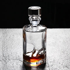 Carafe à whisky ronde en cristal avec bouchon, posée sur une surface en pierre grise, mise en valeur par un éclairage doux.