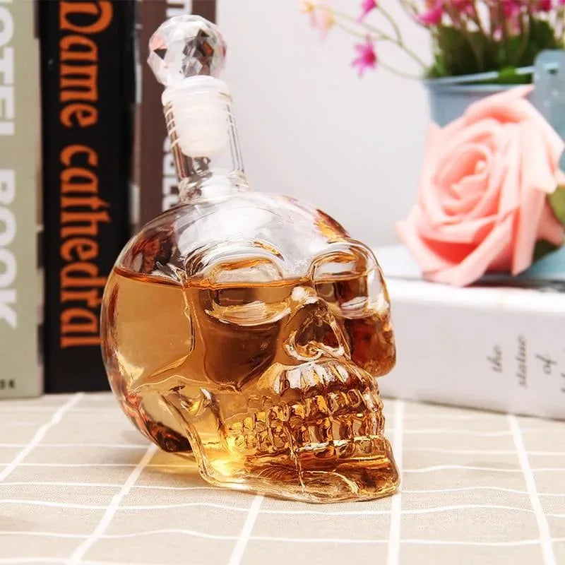 La carafe tête de mort remplie de whisky posée sur un set de table tressé, entourée de livres et d'une rose en décor
