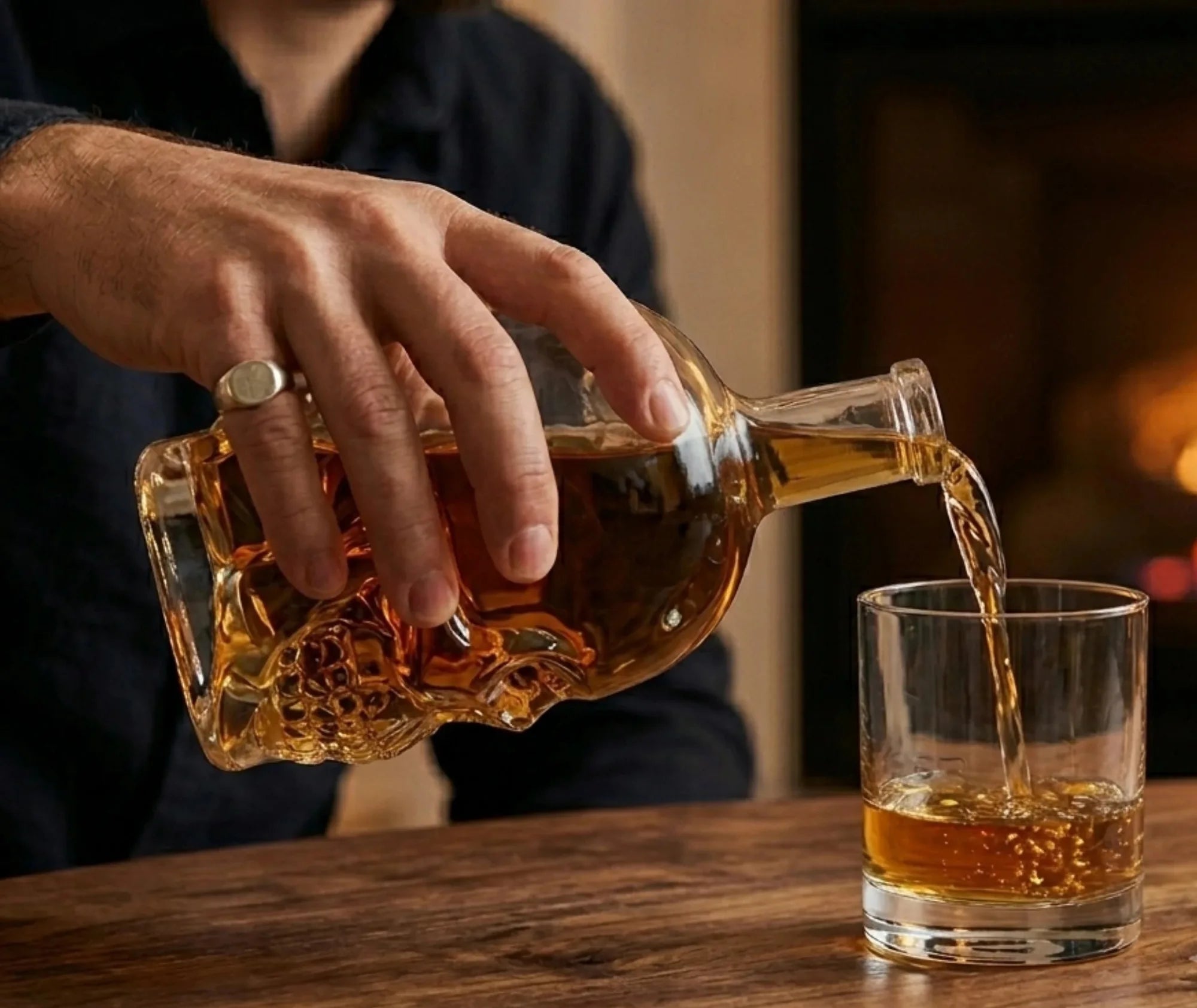 Un homme verse du whisky depuis la carafe tête de mort dans un verre rond, dans une ambiance chaleureuse près d'une cheminée
