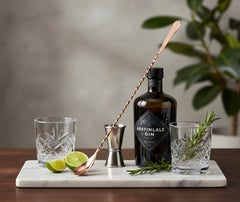 Cuillère à cocktail grande taille en situation avec une bouteille de gin, des verres et des accessoires de bar
