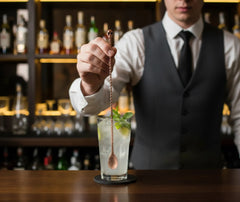 Un barman plonge la cuillère à cocktail tête de mort dans un mojito glacé au bar.