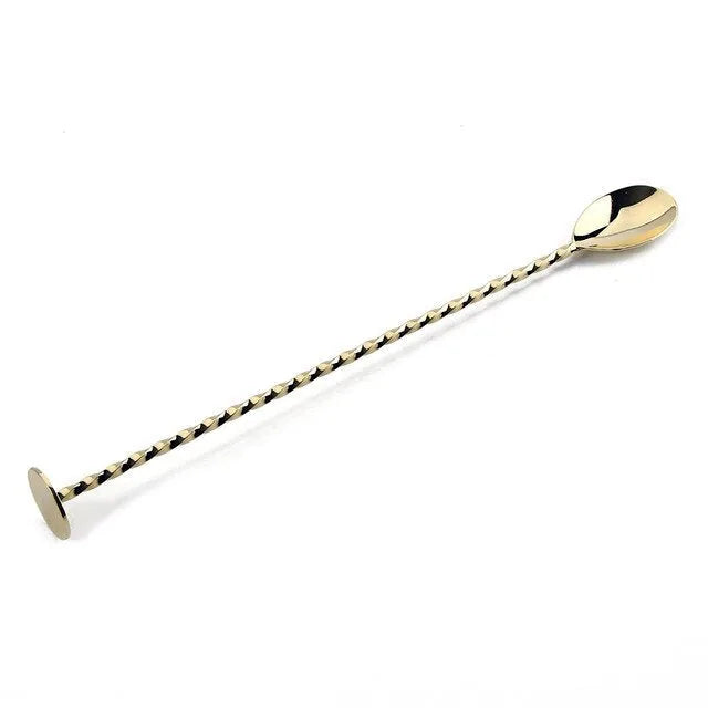 Cuillère à cocktail torsadée dorée présentée seule sur fond blanc