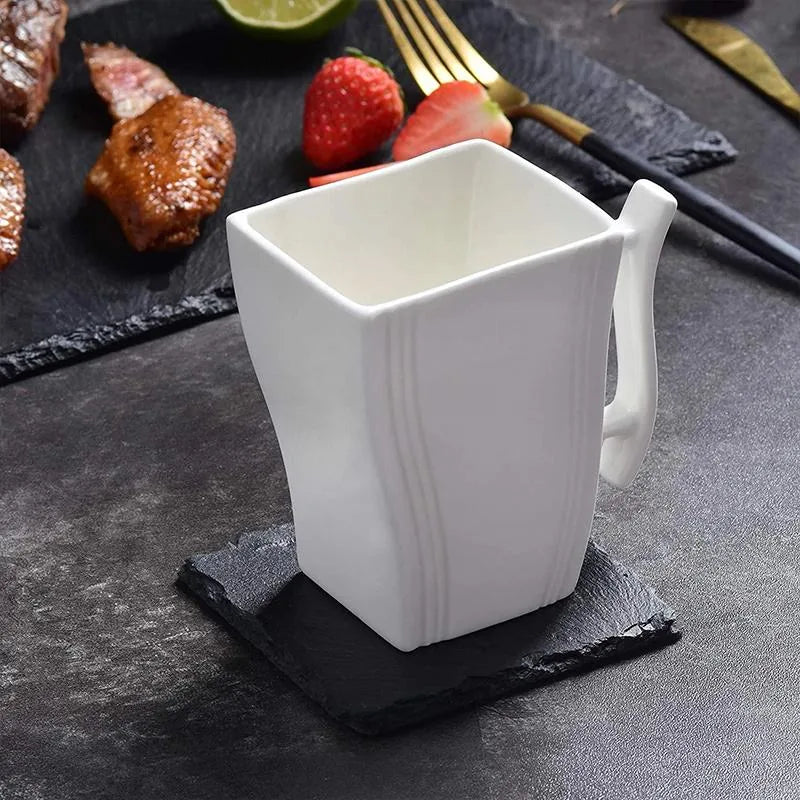 Dessous de verre en ardoise sur une table dressée avec tasse blanche, viande grillée, fraises et couverts dorés