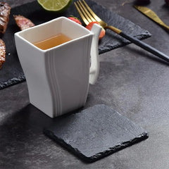 Dessous de verre en ardoise sous une tasse de thé accompagnée de fraises et de viande grillée sur table sombre