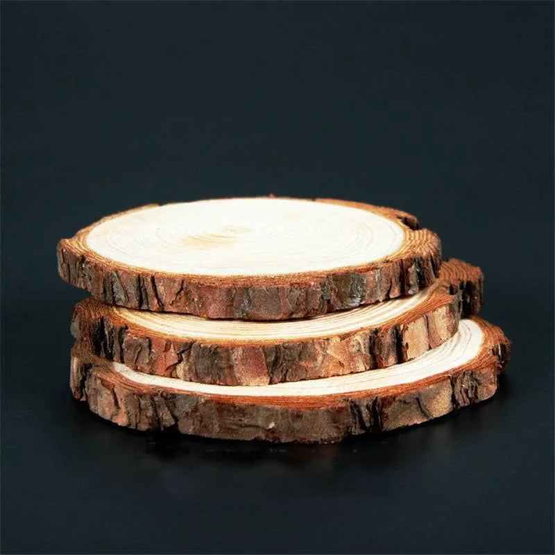 Trois dessous de verre en bois brut empilés, écorce apparente et cernes de croissance visibles sur fond noir.