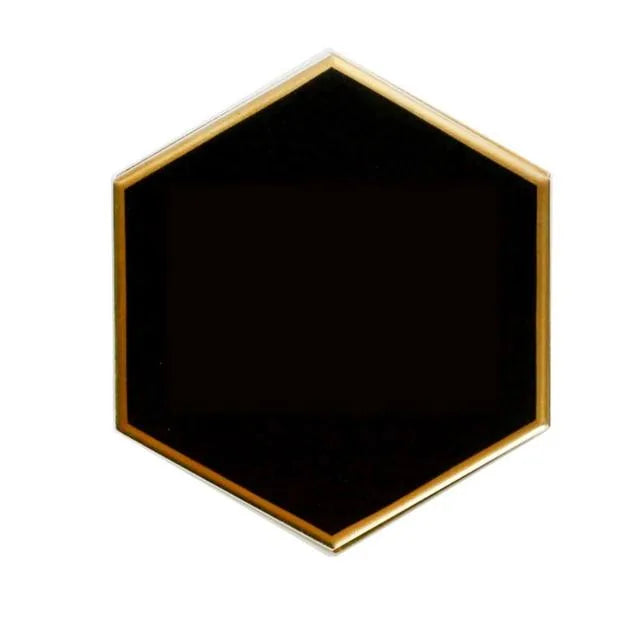 Dessous de verre hexagonal noir avec liseré doré, photographié seul sur fond blanc.