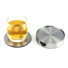 Sur fond blanc, un verre de boisson ambrée repose sur un dessous de verre en inox, à côté du boîtier empilé contenant les autres dessous de verre.