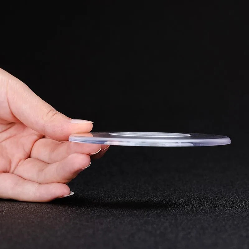 Dessous de verre lumineux tenu de profil dans une main, appareil éteint et transparent, bouton marche-arrêt visible sur la tranche.