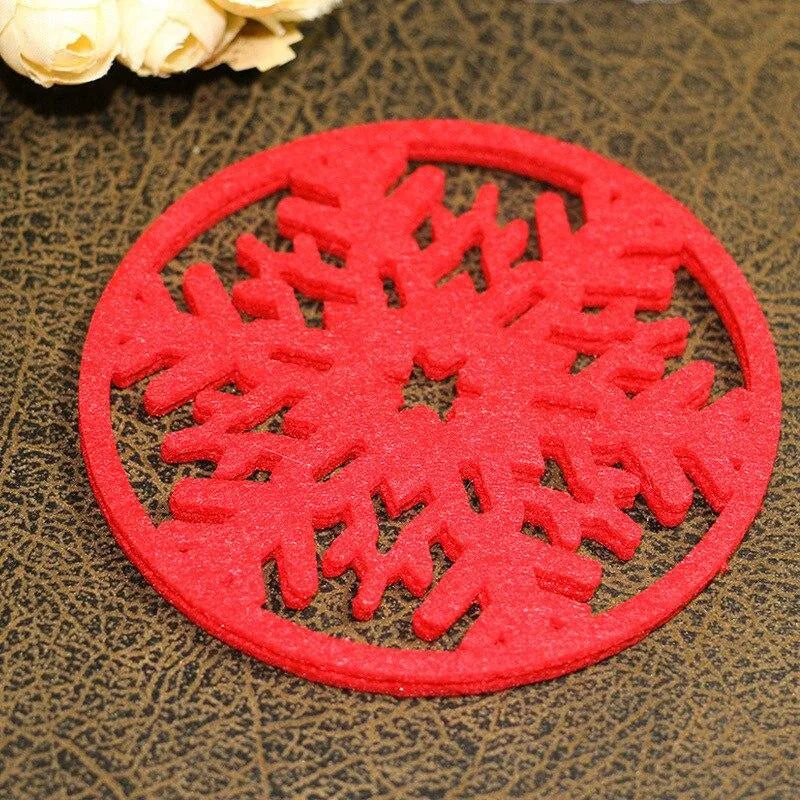 Gros plan sur un dessous de verre rouge en forme de flocon de neige ajouré, posé sur une table en cuir avec des fleurs blanches en arrière-plan