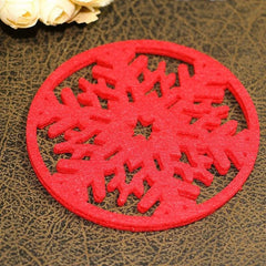 Gros plan sur un dessous de verre rouge en forme de flocon de neige ajouré, posé sur une table en cuir avec des fleurs blanches en arrière-plan